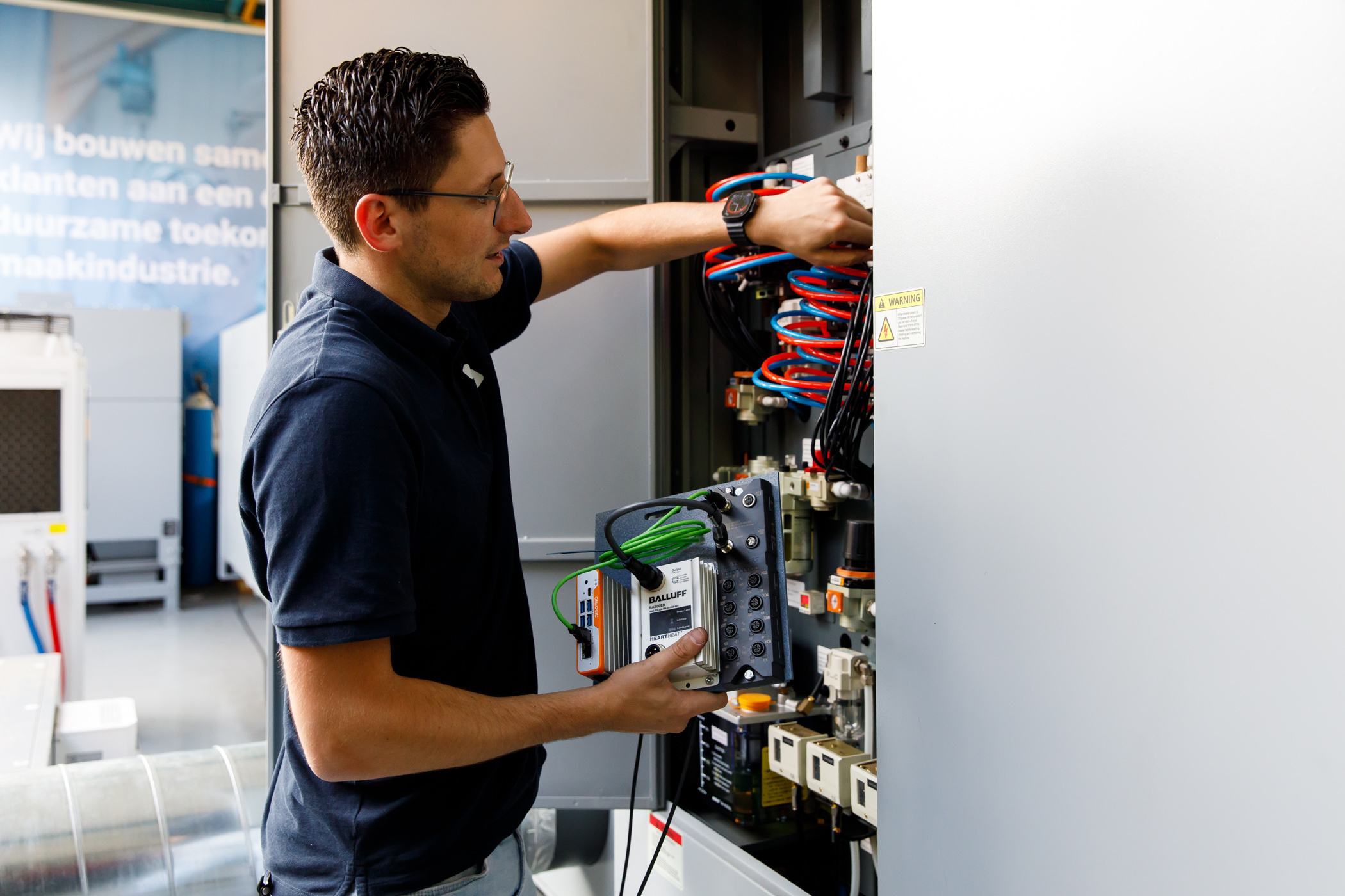 Technician is working on a control cabinet in a production hall