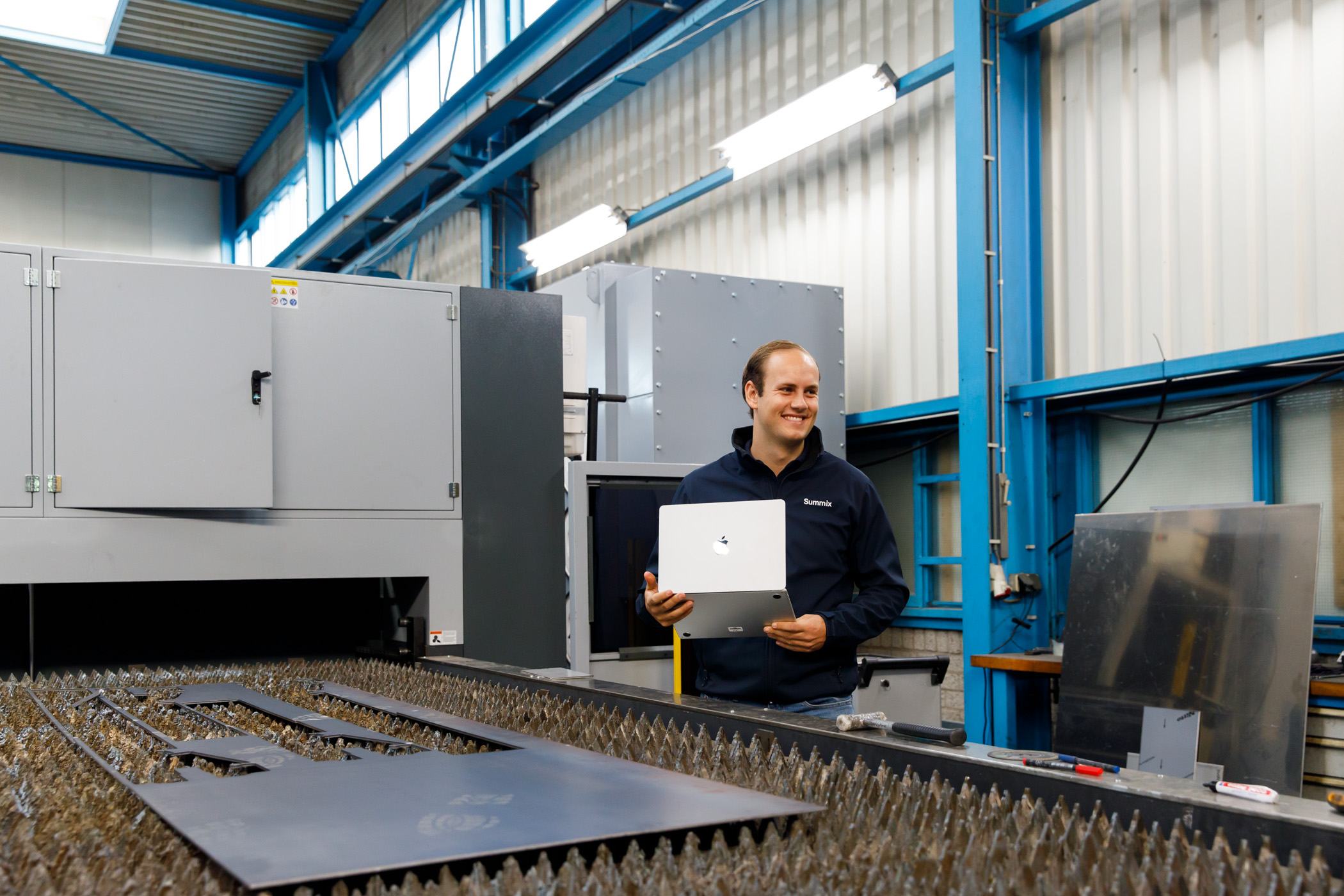 Summix colleague with laptop near a laser cutting machine