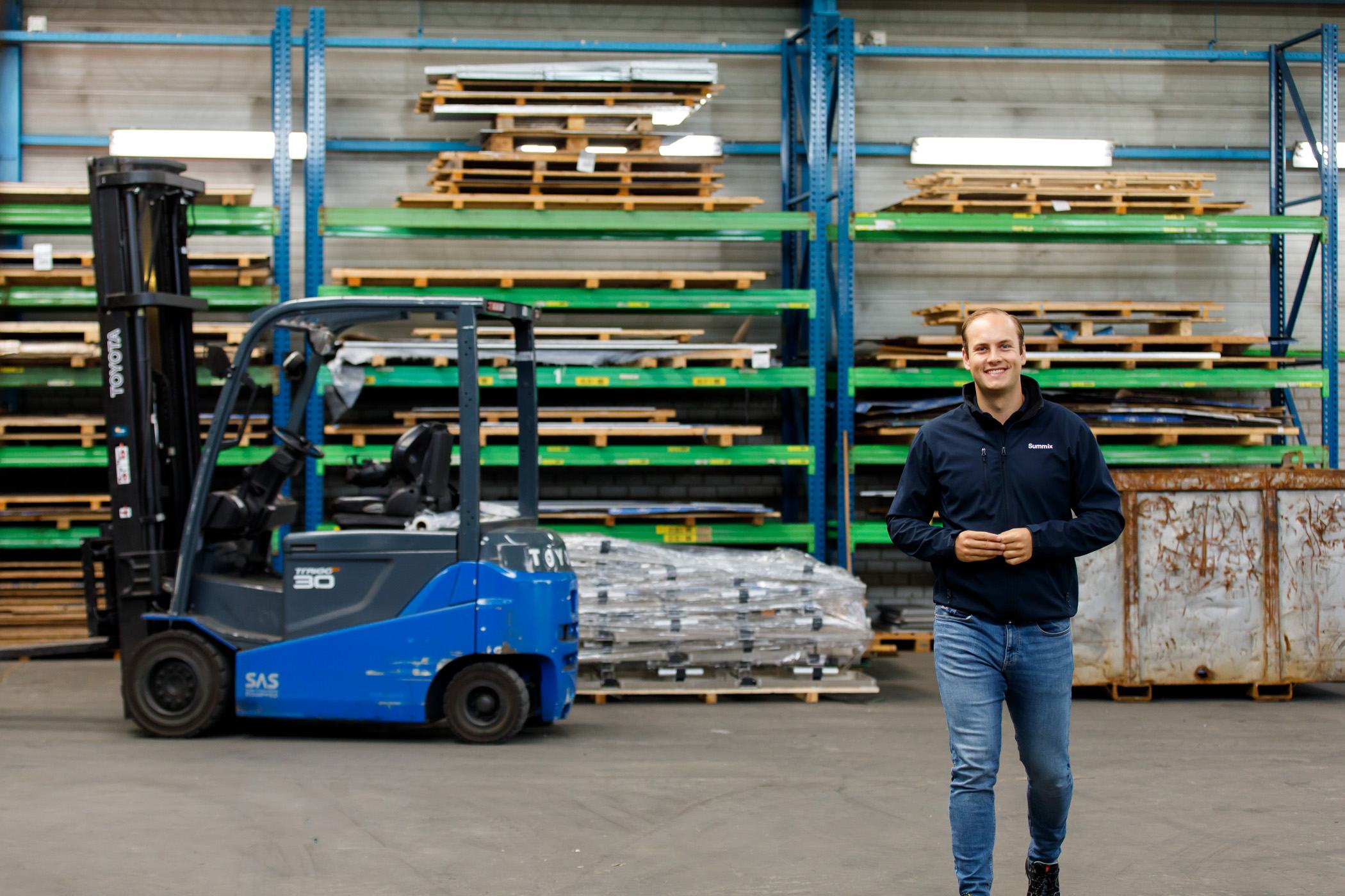 Summix colleague walks through the production hall past a forklift and storage racks